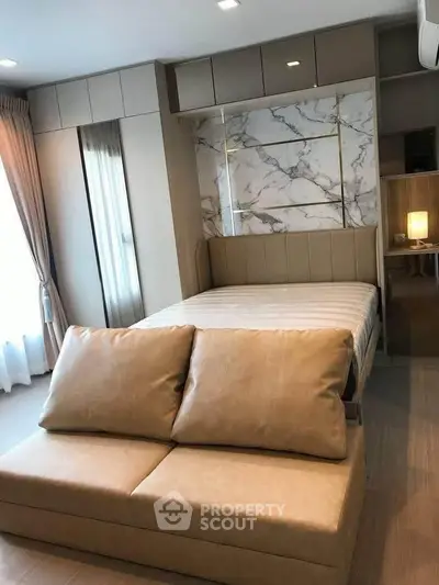 Modern bedroom with stylish marble accent wall and cozy sofa in a chic apartment.