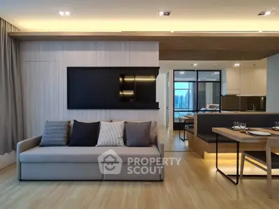 Modern living room with sleek design and open kitchen layout, featuring stylish furniture and ambient lighting.