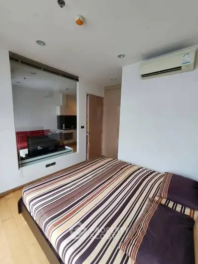 Modern bedroom with striped bedding, wall-mounted air conditioner, and mirrored wall reflecting a cozy living space.