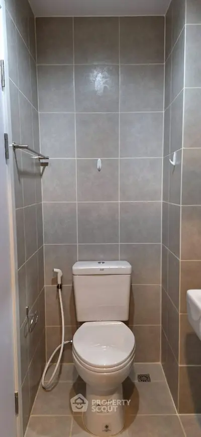 Modern bathroom with tiled walls and toilet in a compact space.