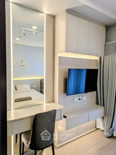 Modern bedroom with sleek built-in desk and wall-mounted TV, perfect for urban living.