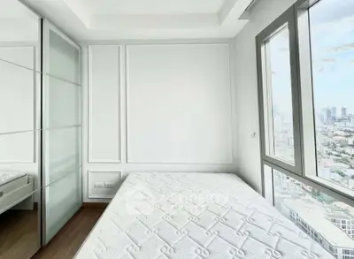 Bright bedroom with large windows offering stunning city views and modern decor.