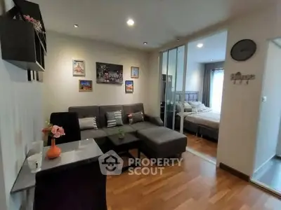 Modern living room with stylish decor and cozy seating adjacent to a bedroom with sliding glass doors.