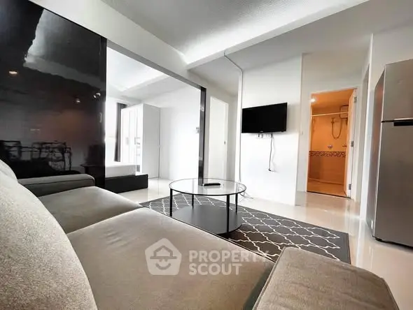 Modern living room with sleek furniture and wall-mounted TV in a stylish apartment.