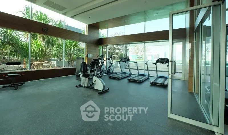 Spacious modern gym with large windows and exercise equipment in a luxury residential building.