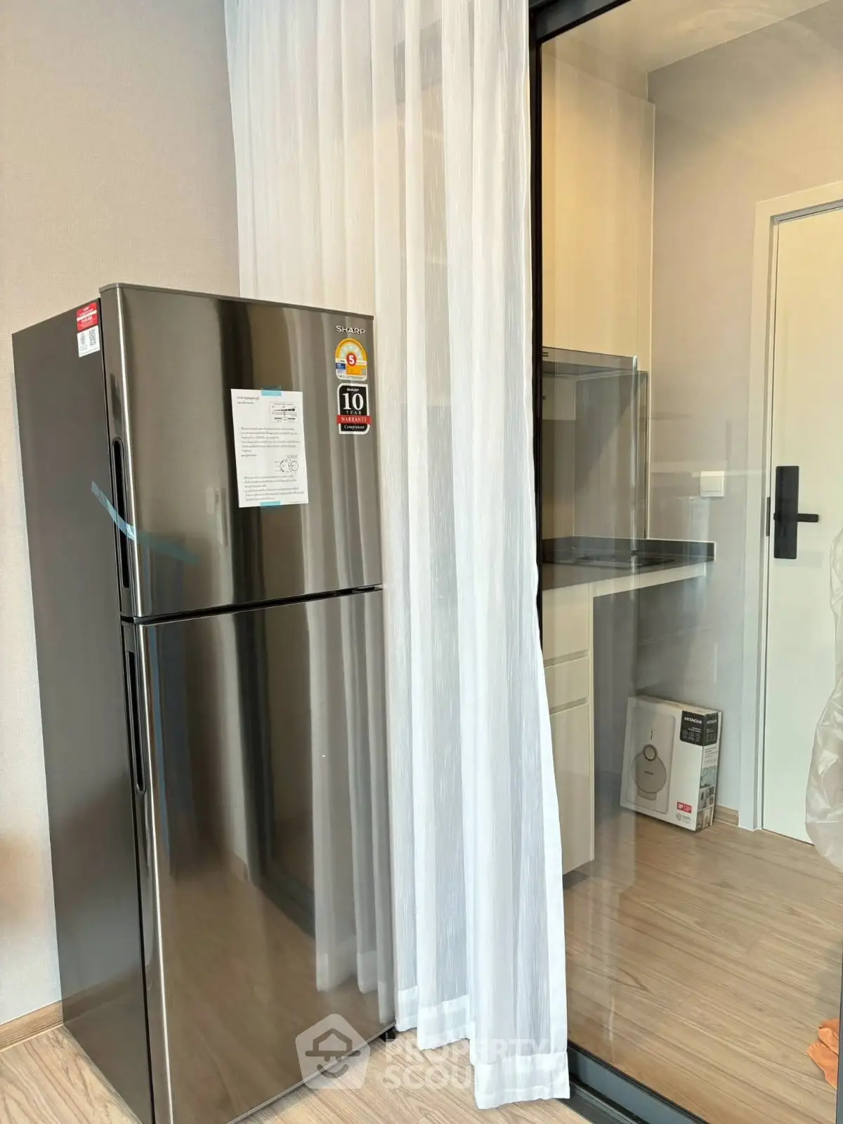 Modern kitchen with sleek stainless steel fridge and glass partition for stylish living.