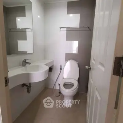 Modern bathroom with sleek fixtures and neutral tones, featuring a stylish sink and toilet.