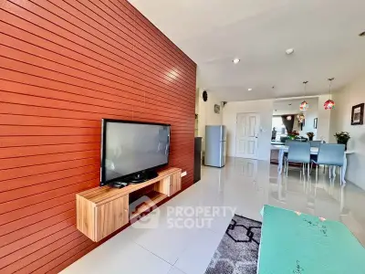 Modern living room with sleek TV setup and open dining area in stylish apartment.
