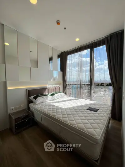 Modern bedroom with floor-to-ceiling windows offering stunning city views, featuring a comfortable bed and elegant decor.