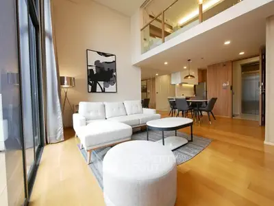 Modern open-plan living room with stylish furniture and high ceilings in a luxury apartment.