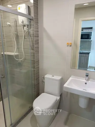 Modern bathroom with glass shower and sleek fixtures in contemporary apartment.