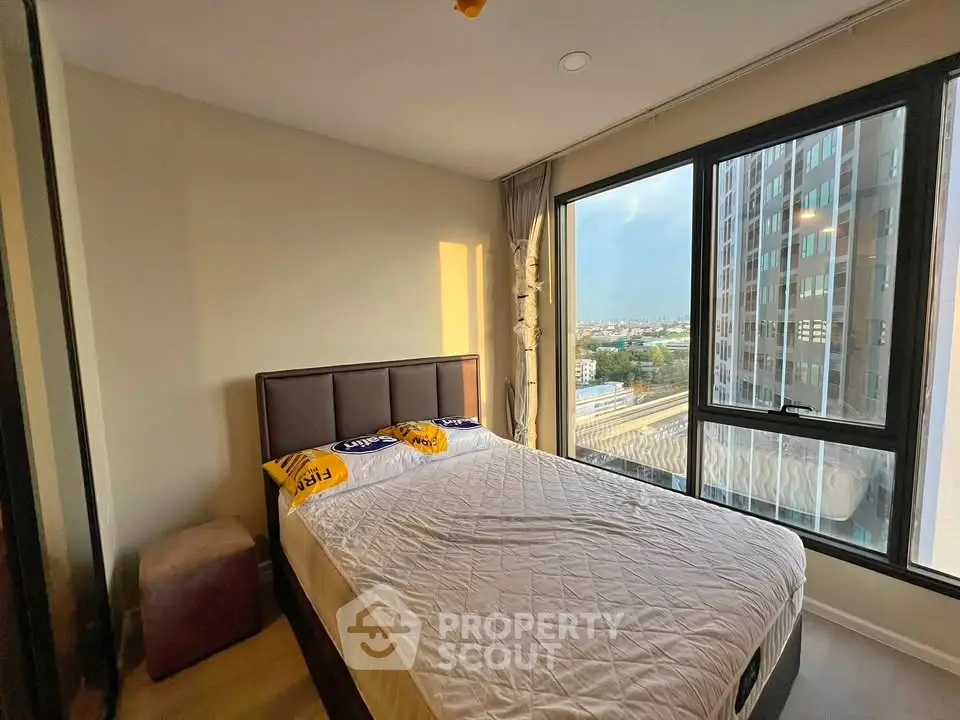 Modern bedroom with large windows offering stunning city views in a high-rise apartment.