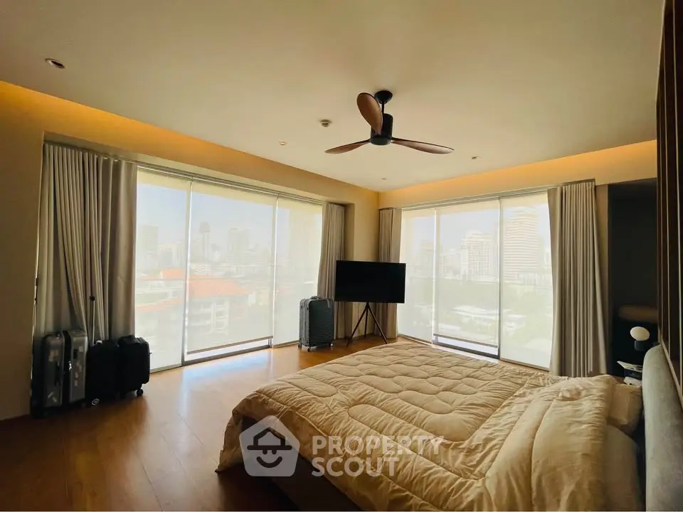 Spacious bedroom with city view, modern decor, and natural light.