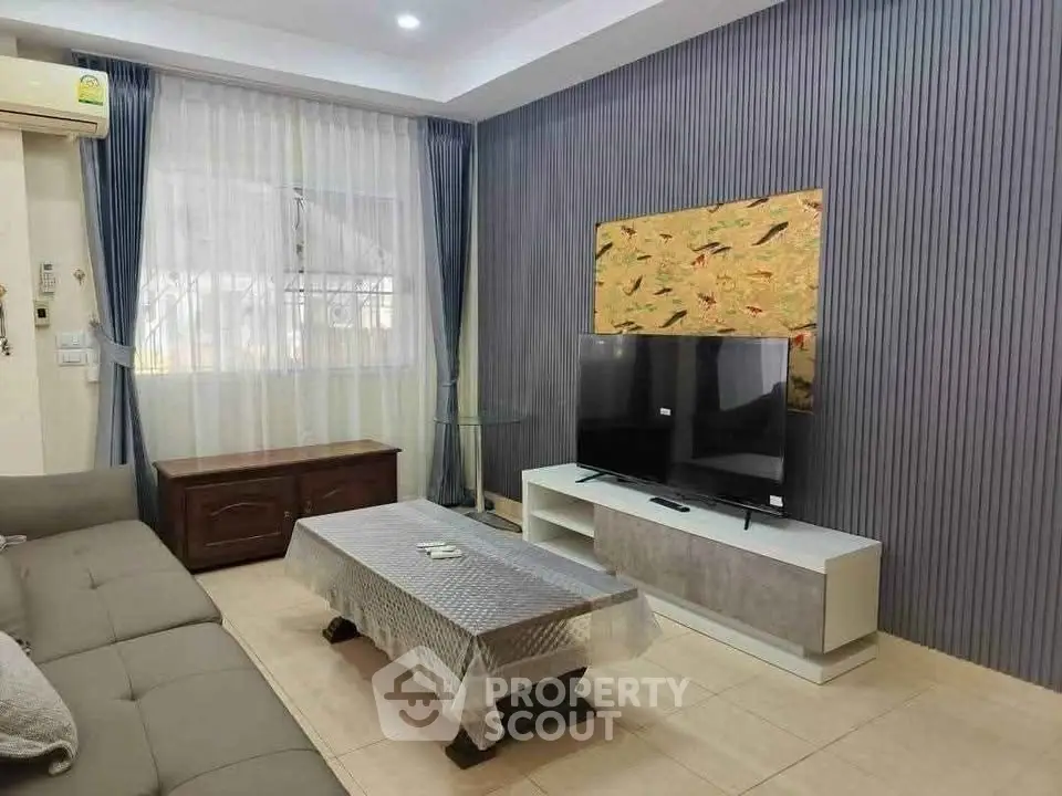 Modern living room with stylish decor and large TV, perfect for relaxation and entertainment.