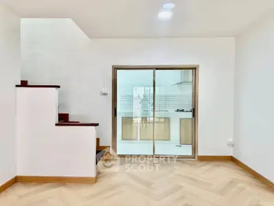 Modern interior with elegant staircase and open kitchen layout, featuring sleek wooden flooring and bright lighting.