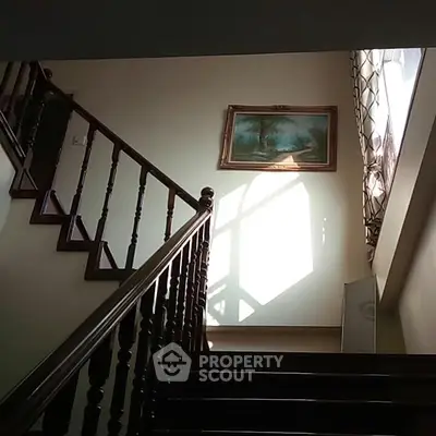 Elegant staircase with wooden railing and natural light in a cozy home