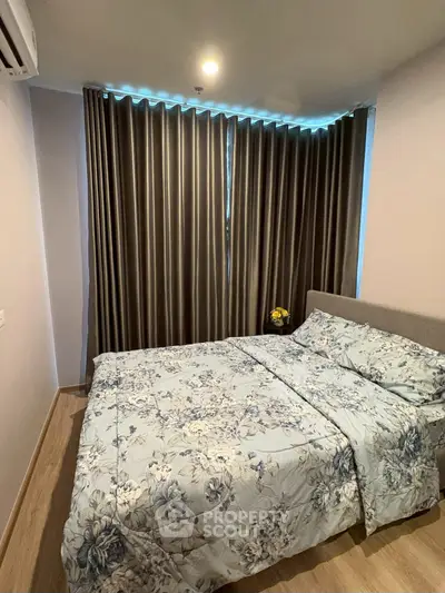 Cozy bedroom with floral bedding and elegant curtains in modern apartment.