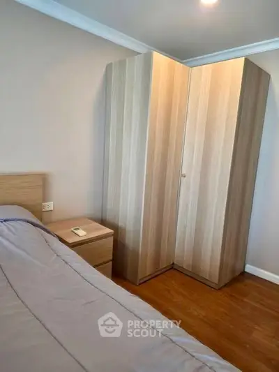 Cozy bedroom with wooden wardrobe and bedside table, perfect for modern living.