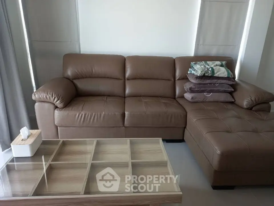 Modern living room with stylish brown leather sofa and glass-top coffee table