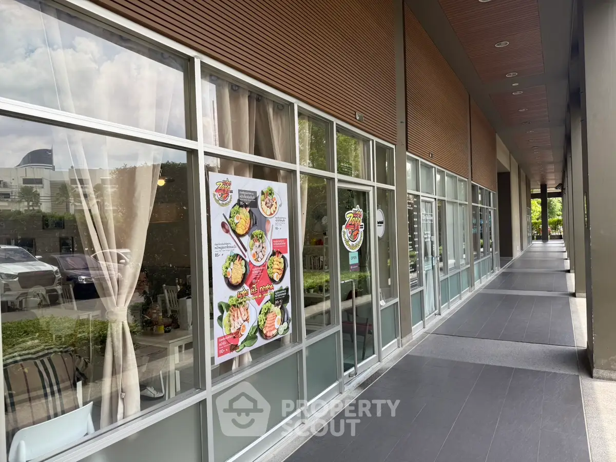 Modern commercial storefront with glass windows and outdoor walkway in urban setting.