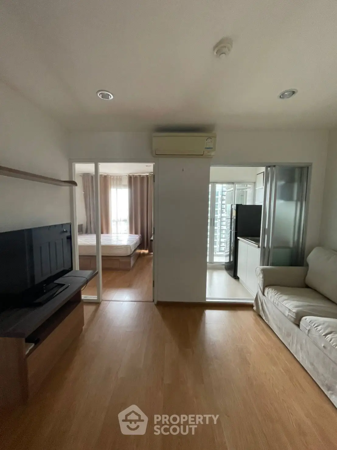 Cozy apartment with modern living room and bedroom, featuring wooden flooring and air conditioning.