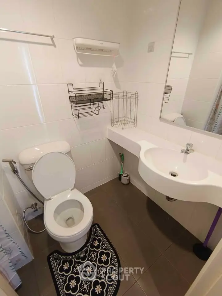 Compact modern bathroom with wall-mounted sink and toilet, featuring sleek white tiles and practical storage solutions.