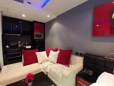 Modern living room with stylish kitchen, featuring red accents and cozy seating area.