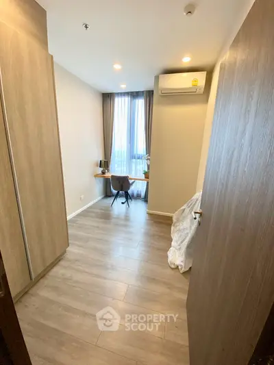 Modern study room with wooden flooring and natural light, featuring a sleek desk and chair setup.