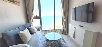 Modern living room with ocean view, elegant sofa, and wall-mounted TV.