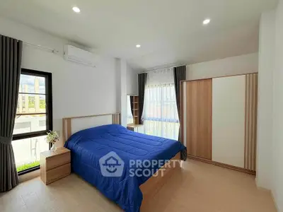 Modern bedroom with blue bedding, wooden furniture, and natural light.