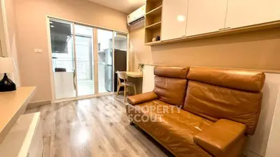 Modern living room with leather sofa and open kitchen layout in stylish apartment.