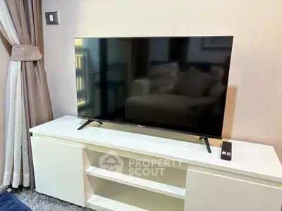 Modern living room with sleek TV on white console and elegant curtains