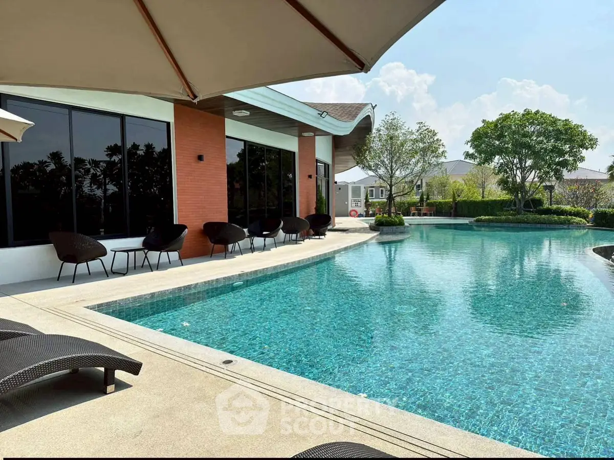 Luxurious poolside view with modern seating and lush greenery, perfect for relaxation and leisure.