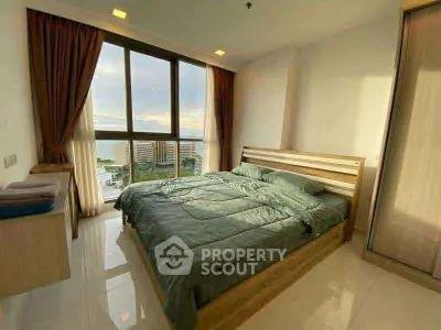 Spacious bedroom with large window offering stunning city view, modern decor, and ample natural light.