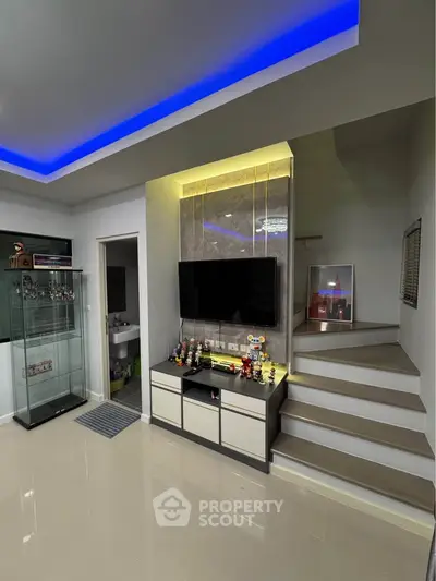 Modern living room with sleek TV setup and illuminated ceiling