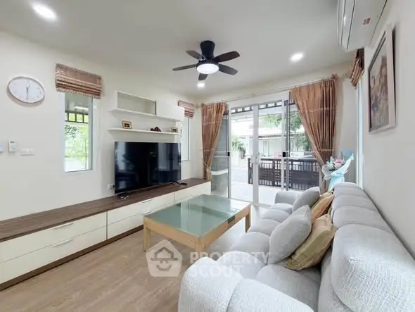 Spacious living room with modern decor and large windows opening to a balcony.