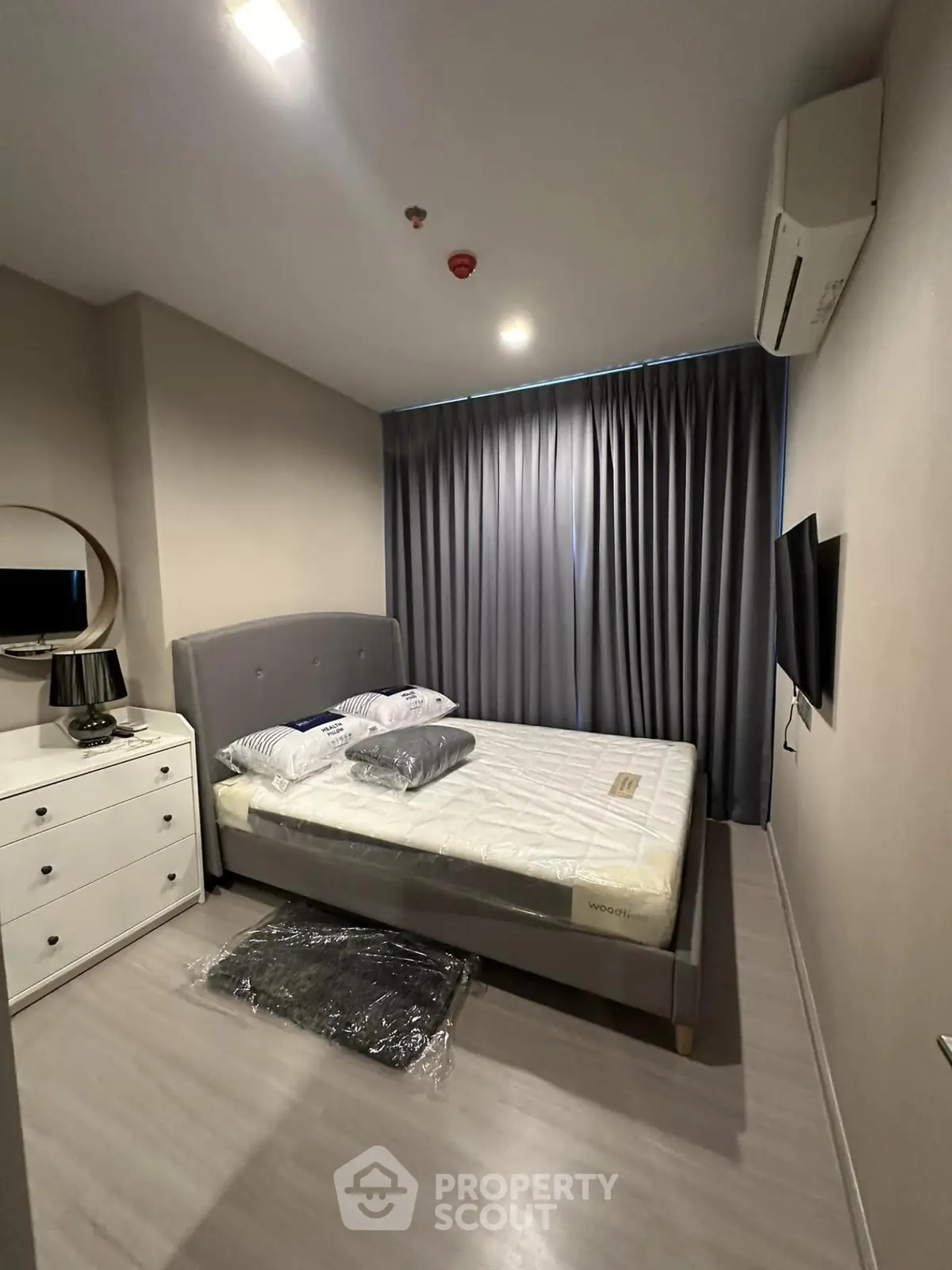 Modern bedroom with sleek design, featuring a comfortable bed, stylish dresser, and wall-mounted TV.