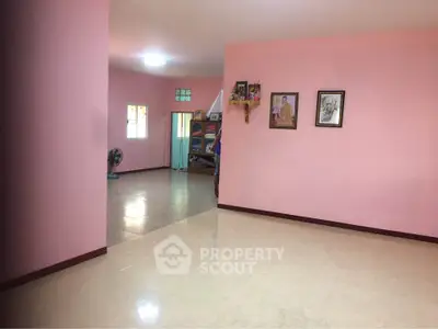 Spacious pink-walled living area with tiled flooring and natural light, ideal for cozy family gatherings.