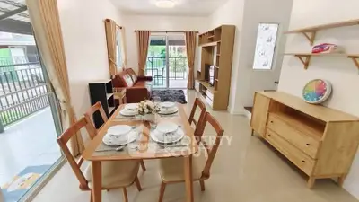 Spacious open-plan living and dining area with elegant wooden furniture and large windows.