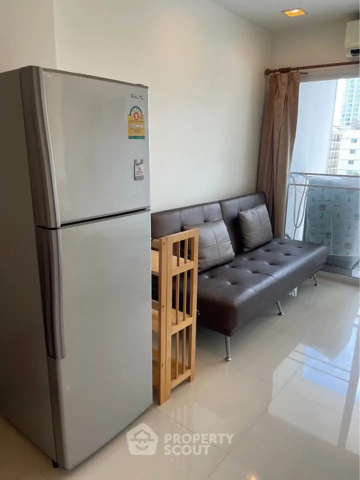 Modern apartment with sleek fridge and cozy seating area near balcony.