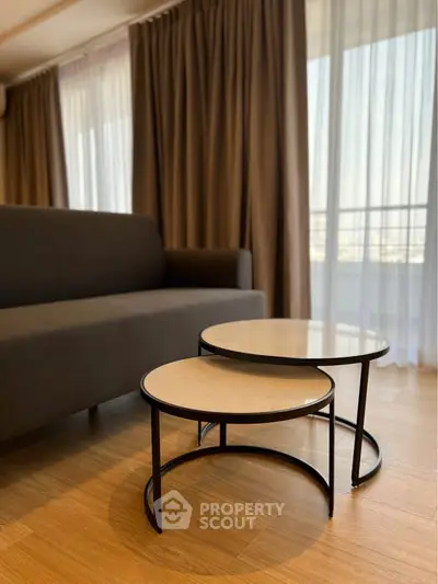 Modern living room with stylish nested coffee tables and elegant curtains.