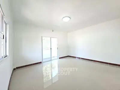 Spacious empty living room with glossy tiled floors and large window for natural light.