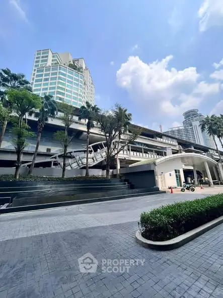 Modern urban building exterior with lush landscaping and clear blue sky.