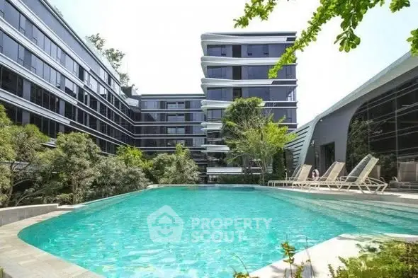 Luxurious modern apartment complex with stunning pool and lush greenery.