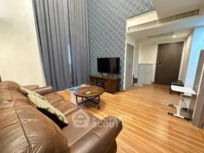 Spacious living room with modern decor and wooden flooring, featuring a cozy leather sofa and stylish TV setup.