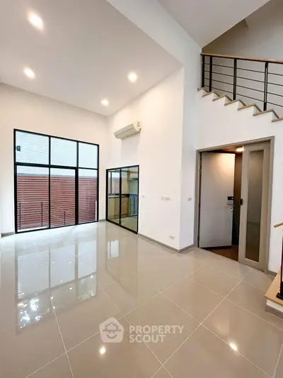 Spacious modern living room with high ceilings and large windows in a contemporary home.
