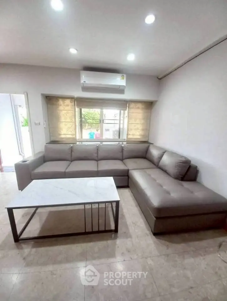 Spacious living room with modern L-shaped sofa and sleek marble coffee table.