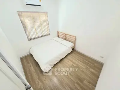 Minimalist bedroom with wooden flooring and natural light