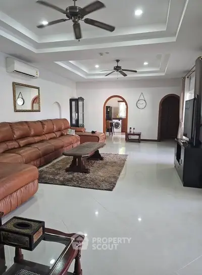 Spacious living room with leather sofa and modern decor, ideal for family gatherings.