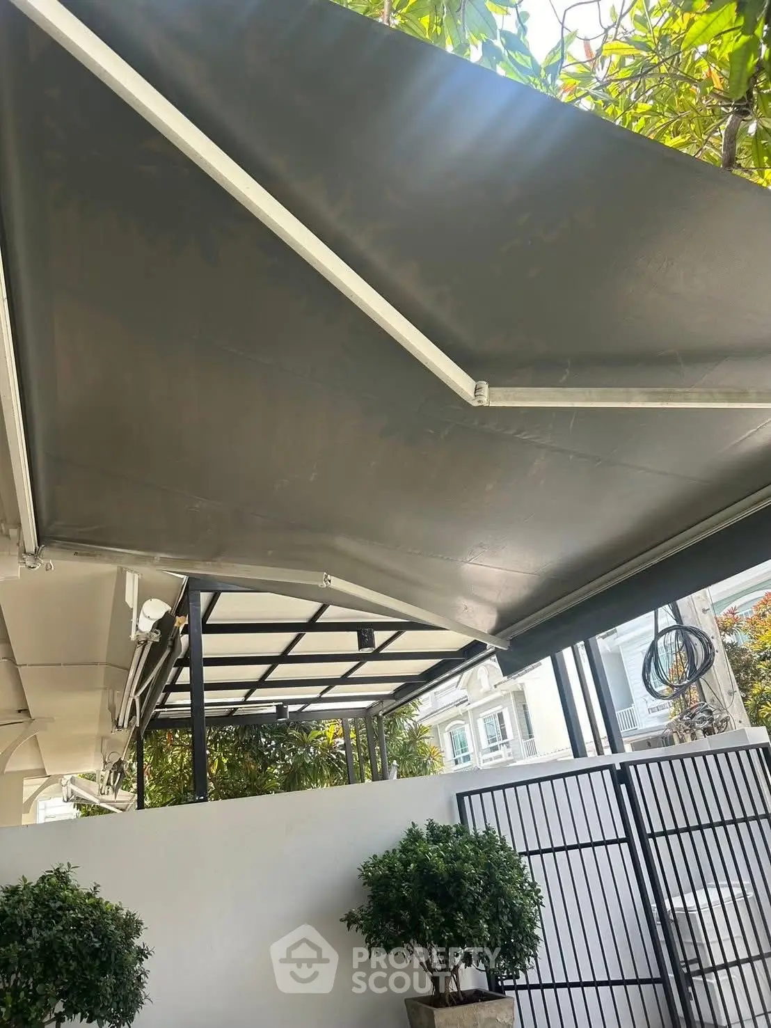 Modern outdoor patio with sleek awning and potted plants, perfect for relaxation.